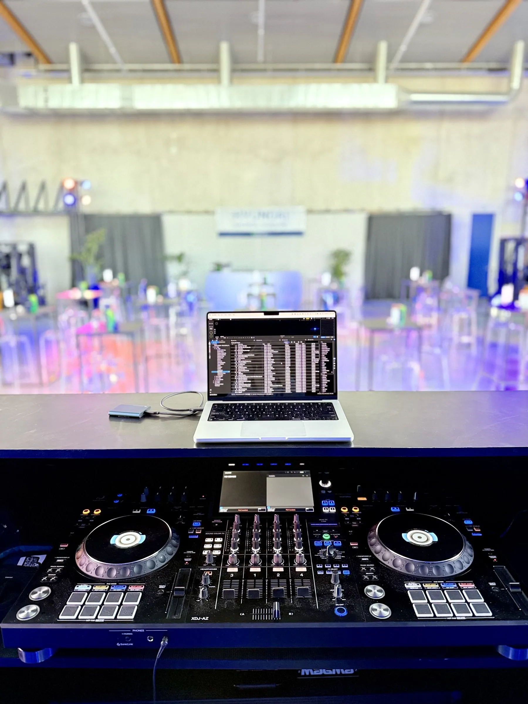 XDJ-AZ en laptop in de DJ-booth, met de feestzaal op de achtergrond