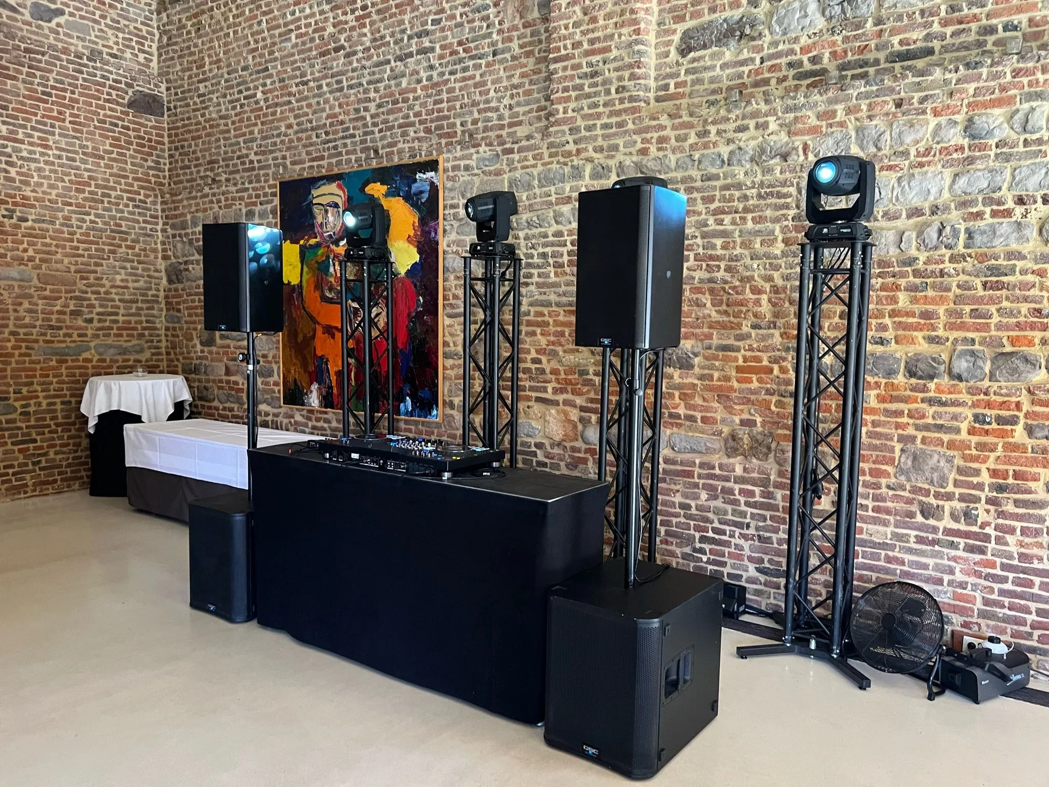 DJ-opstelling voor een trouwfeest in een zaal met bakstenen muren