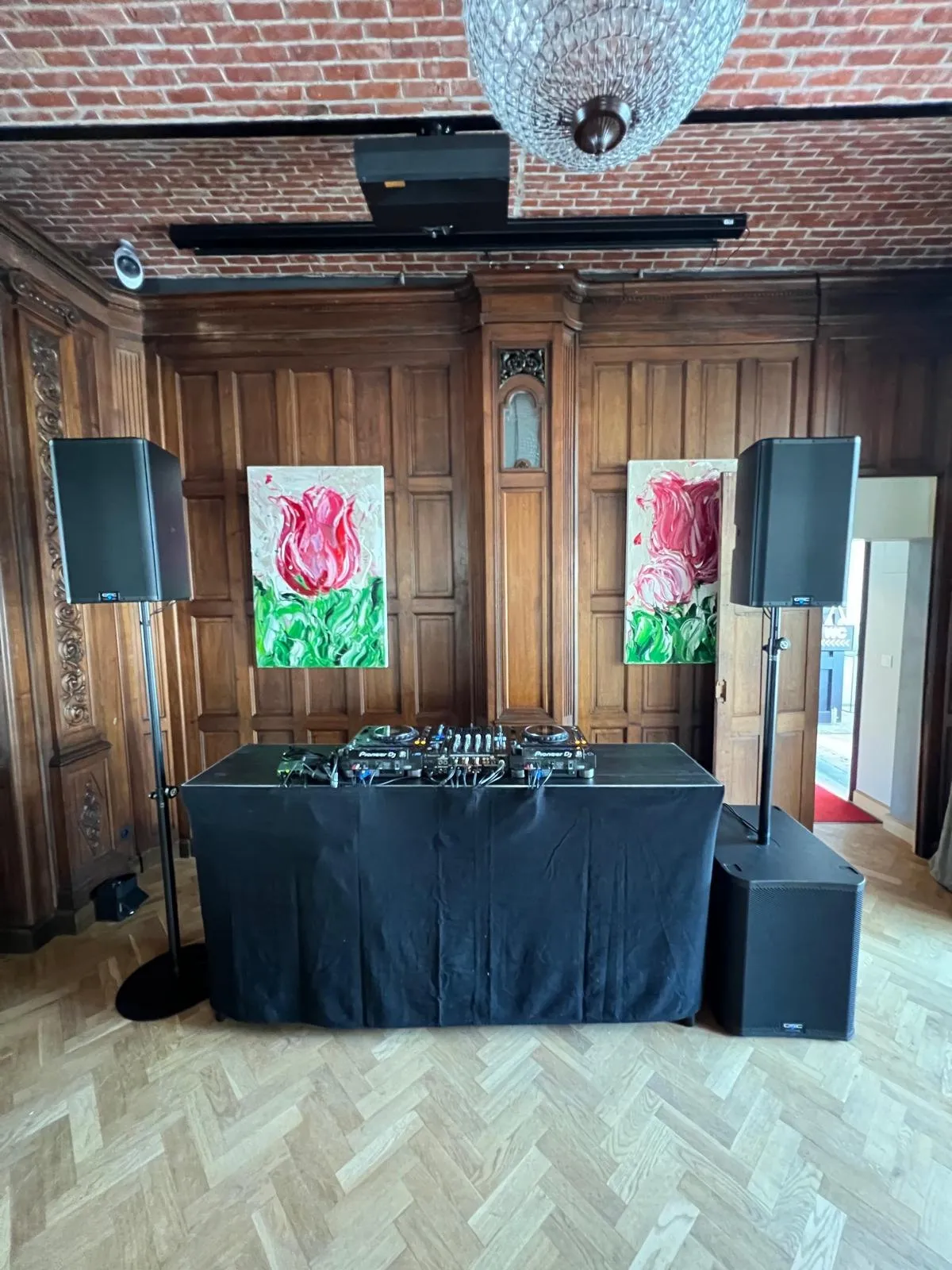 DJ-opstelling in een zaal met houten lambrisering en visgraatvloer