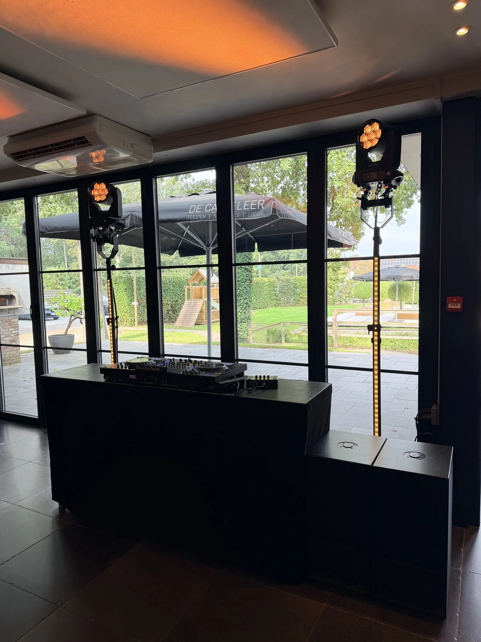 DJ-booth met moving heads in een feestzaal met grote ramen